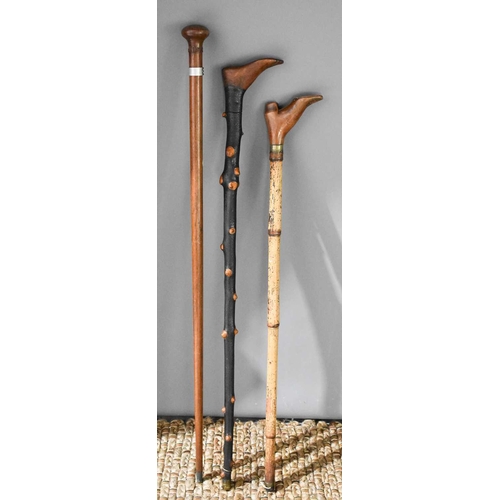 241 - A group of three walking sticks, comprising a bamboo cane with shoe form handle, a blackened cabbage... 