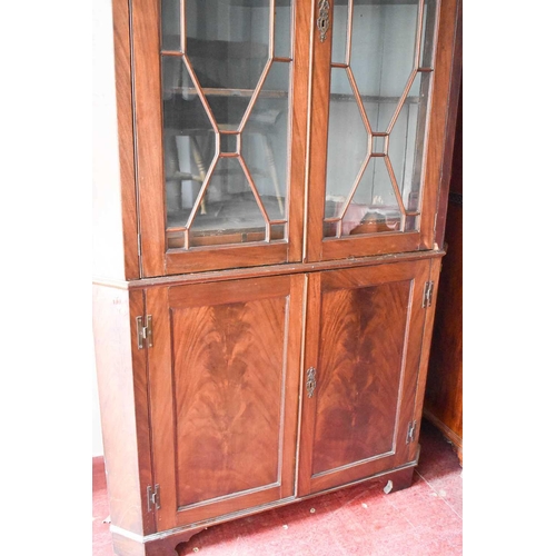 525 - An unusual 19th century mahogany corner cupboard, the astragal glazed doors enclosing a shaped shelv... 