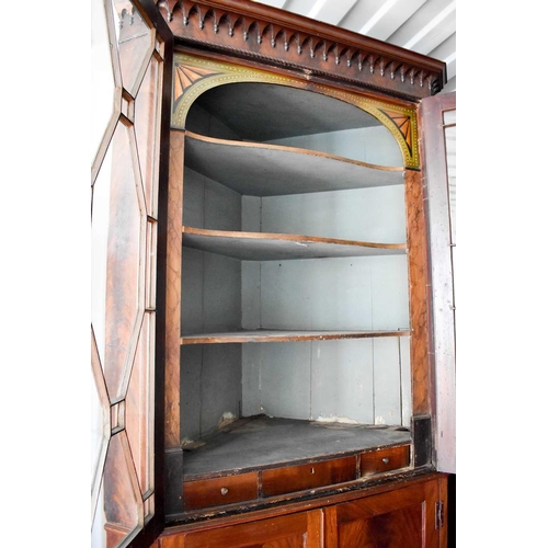 525 - An unusual 19th century mahogany corner cupboard, the astragal glazed doors enclosing a shaped shelv... 