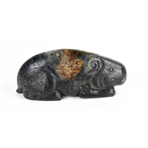 107 - A Qing Dynasty black jade mythical beast, of large pebble form, shown crouched with the legs folded ... 