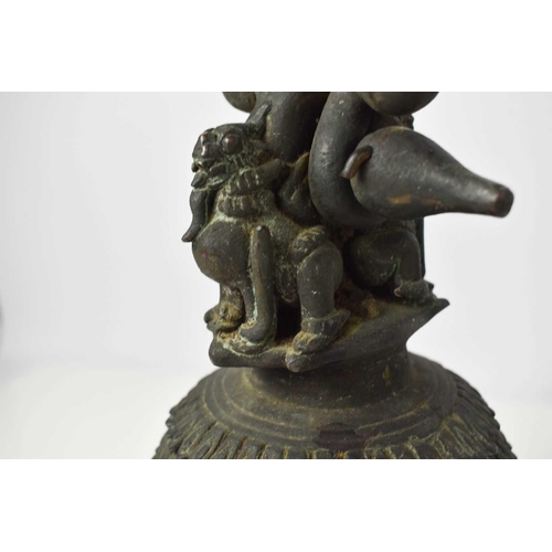 110 - A Tibetan bronze bell, cast with two dragons to the top and hoop handle, 36cm high.