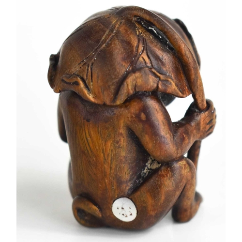 156 - A Japanese carved wooden netsuke of a monkey sheltering under a leaf, with glass eyes and signed mot... 