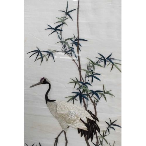 215 - A pair of Chinese embroidered panels, depicting a bird and crane amidst bullrushes, 110 by 46cm.