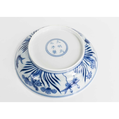 25 - A Chinese blue and white dish, painted with fish against a wave ground, with waterlilies, in undergl... 