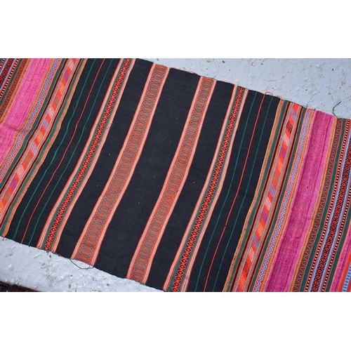 277 - A Middle Eastern hand woven wool sadllebag together with a handmade brightly coloured cotton runner ... 