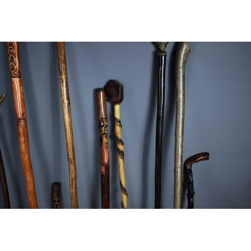 355 - A collection of walking canes and staffs to include a cane carved with a snake spiralling around the... 