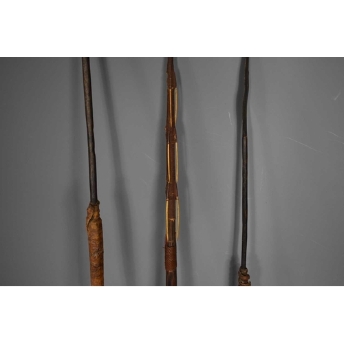 358 - A group of three tribal hunting spears, one with quill barbs and carvings the other two spears with ... 