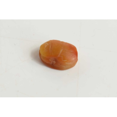 364 - A tiny Egyptian scarab beetle bead carved from an amber coloured stone, the base having a carved hie... 