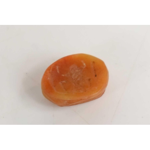 364 - A tiny Egyptian scarab beetle bead carved from an amber coloured stone, the base having a carved hie... 