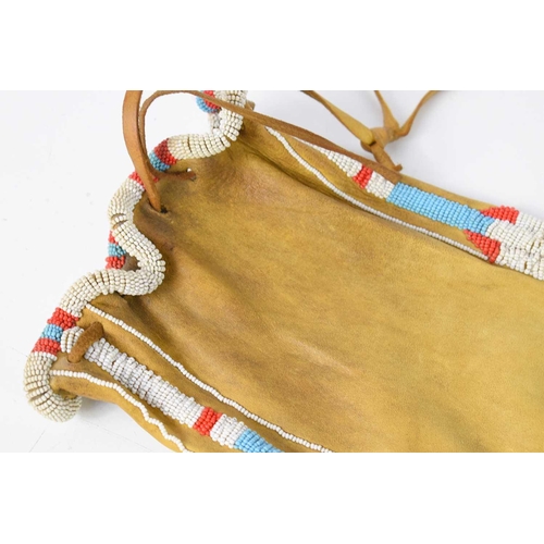 433 - A Native American tanned hide and beaded pipe bag, the coloured beads in a geometric pattern, the ba... 