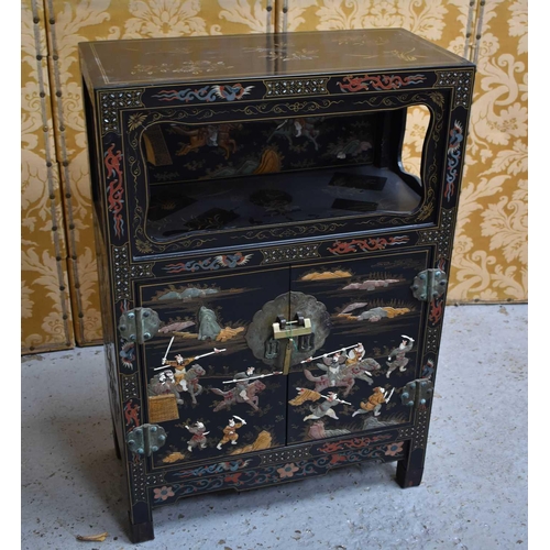 447 - A Chinese cabinet with two doors, shelf, and open shelved compartment, decorated with warriors, with... 