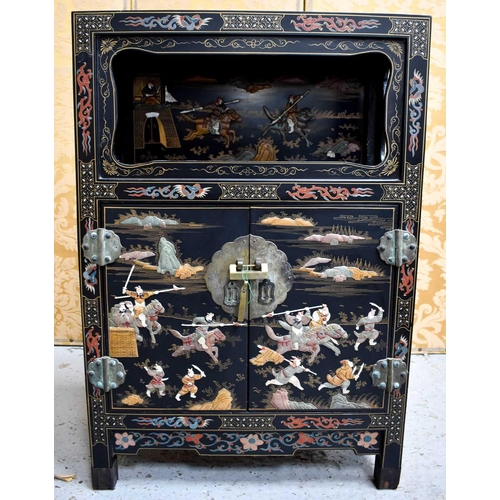 447 - A Chinese cabinet with two doors, shelf, and open shelved compartment, decorated with warriors, with... 