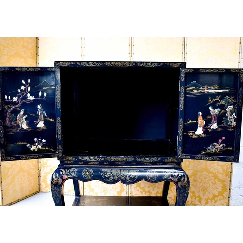 453 - A Chinese black lacquered cabinet on stand, Chinoiserie decorated scenes to outer and inner door pan... 