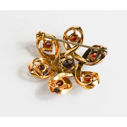 137 - An Edwardian style, 9ct gold, garnet and seed pearl brooch, of scrolling flower head form, the ribbo... 