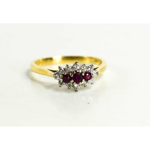 146 - An 18ct gold, diamond and ruby dress ring, of three central rubies, surrounded by twelve diamonds, s... 