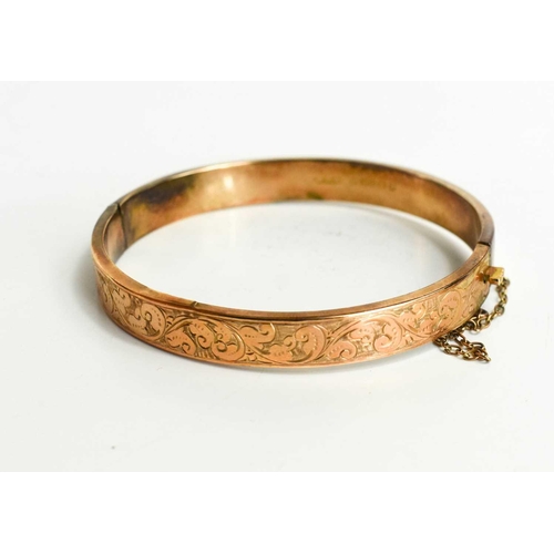 148 - A 9ct gold bangle, decorated with chased scrollwork, with safety chain, and the original presentatio... 