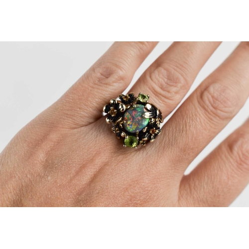 162 - An oval opal, silver and peridot set ring, the branch form shank forming butterflies and flowerheads... 