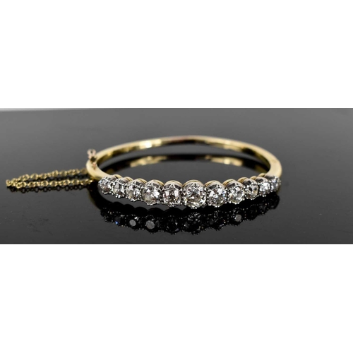 186 - A stunning and impressive diamond and 18ct gold bangle, set with eleven brilliant oval cut diamonds,... 