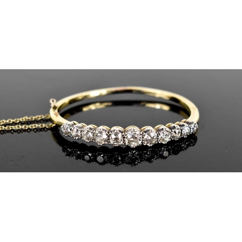 186 - A stunning and impressive diamond and 18ct gold bangle, set with eleven brilliant oval cut diamonds,... 