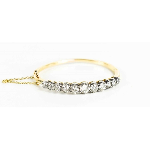 186 - A stunning and impressive diamond and 18ct gold bangle, set with eleven brilliant oval cut diamonds,... 