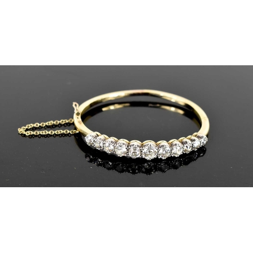 186 - A stunning and impressive diamond and 18ct gold bangle, set with eleven brilliant oval cut diamonds,... 