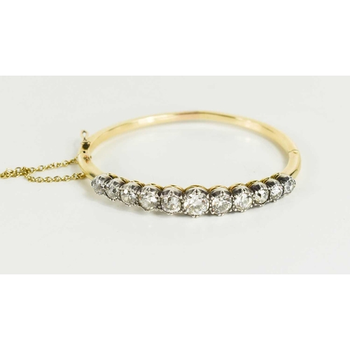 186 - A stunning and impressive diamond and 18ct gold bangle, set with eleven brilliant oval cut diamonds,... 