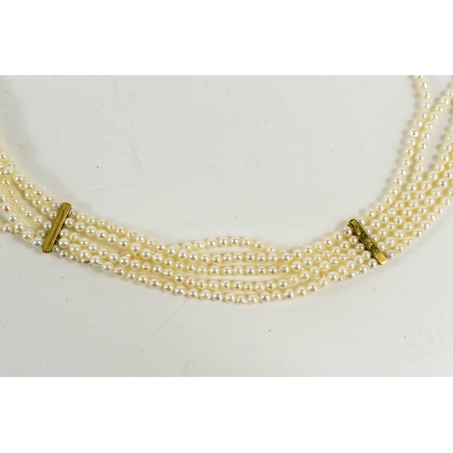 21 - A five strand seed pearl choker with 18ct gold and emerald set clasp in the Byzantine style and four... 