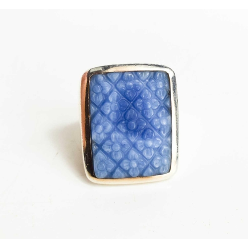 39 - A large Sterling silver ring with a large blue stone, likely agate, carved with a floral pattern wit... 