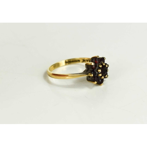 50 - A 9ct gold and garnet flowerhead ring, set with central round cut garnet, surrounded by eight smalle... 