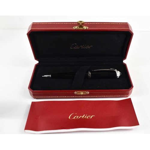 57 - A Cartier ballpoint pen, black composite body and cap, palladium-finish details, blue resin cabochon... 