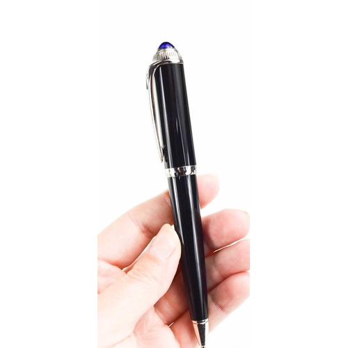 57 - A Cartier ballpoint pen, black composite body and cap, palladium-finish details, blue resin cabochon... 