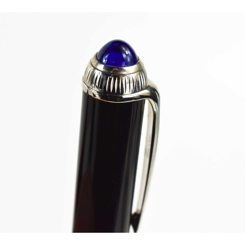 57 - A Cartier ballpoint pen, black composite body and cap, palladium-finish details, blue resin cabochon... 