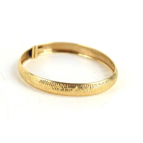 65 - A 9ct gold bangle with repousee finish, with slide clasp, 4.9g.