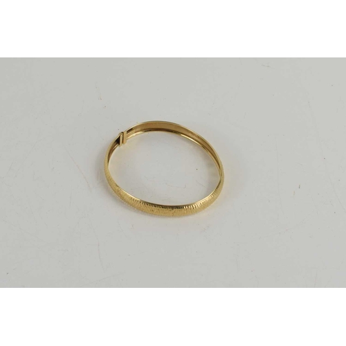 65 - A 9ct gold bangle with repousee finish, with slide clasp, 4.9g.