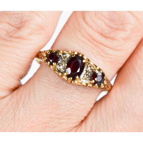 74 - A 9ct gold three stone ring, set with graduated garnets, with two pairs of old cut diamond chips in ... 