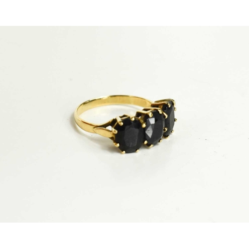 85 - A 9ct gold and dark sapphire three stone ring, each of the oval cut almost black sapphires of approx... 