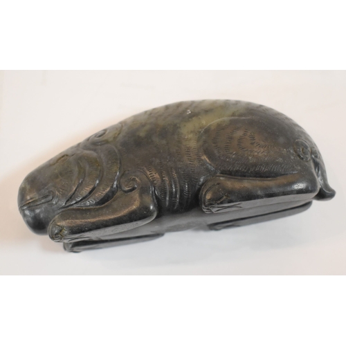 107 - A Qing Dynasty black jade mythical beast, of large pebble form, shown crouched with the legs folded ... 