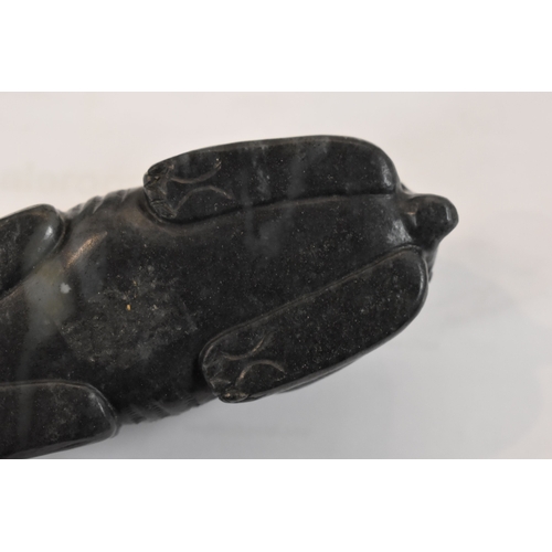 107 - A Qing Dynasty black jade mythical beast, of large pebble form, shown crouched with the legs folded ... 