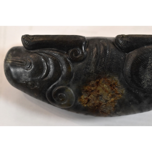 107 - A Qing Dynasty black jade mythical beast, of large pebble form, shown crouched with the legs folded ... 