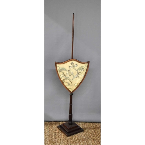 454 - A 19th century mahogany pole fire screen, the rise and fall banner of shield form inset with a silk ... 