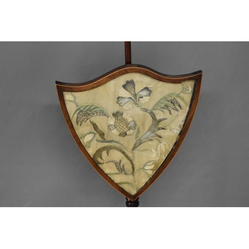 454 - A 19th century mahogany pole fire screen, the rise and fall banner of shield form inset with a silk ... 