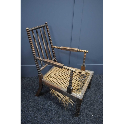 464 - A 19th century regional bobbin turned rosewood and caned armchair, the cane work A/F.