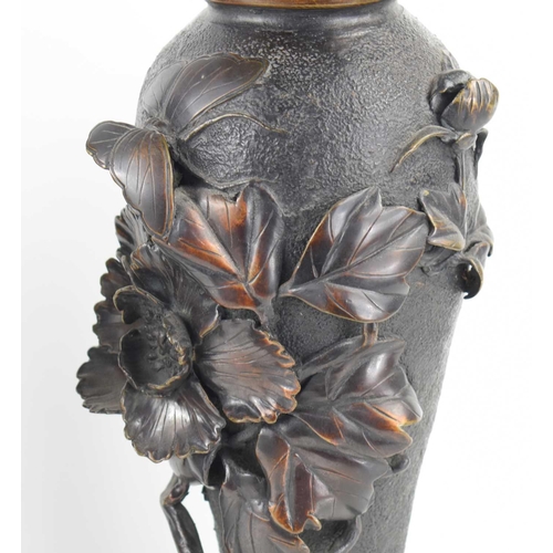 119 - A pair of Japanese bronze vases, with relief decoration depicting a butterfly among a sprays of flow... 