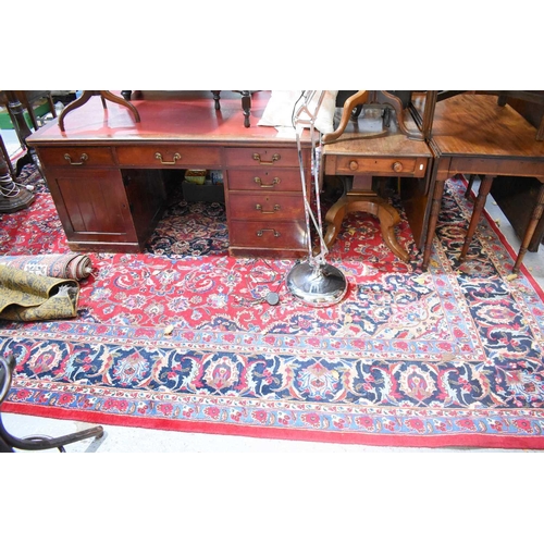 607 - A large Middle Eastern red ground rug with stylised floral motifs to the centre and repeating border... 