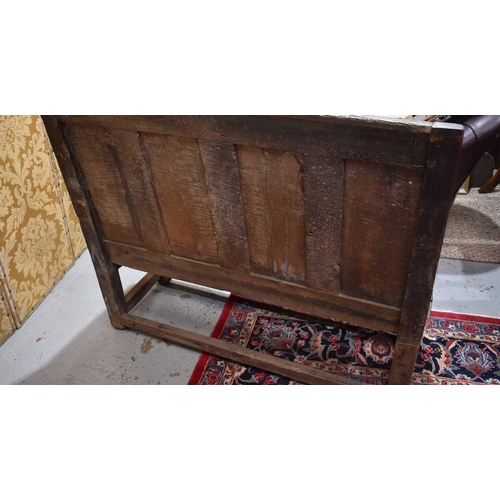 660 - An 18th century oak or elm settle, the high back having a four panel backrest and shaped open arms, ... 