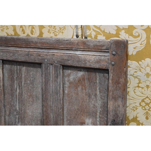 660 - An 18th century oak or elm settle, the high back having a four panel backrest and shaped open arms, ... 