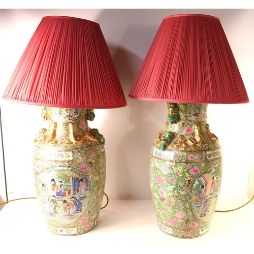 296 - A pair of 20th century Chinese Famille Rose vasiform lamps, fitted for electric, with red pleated sh... 