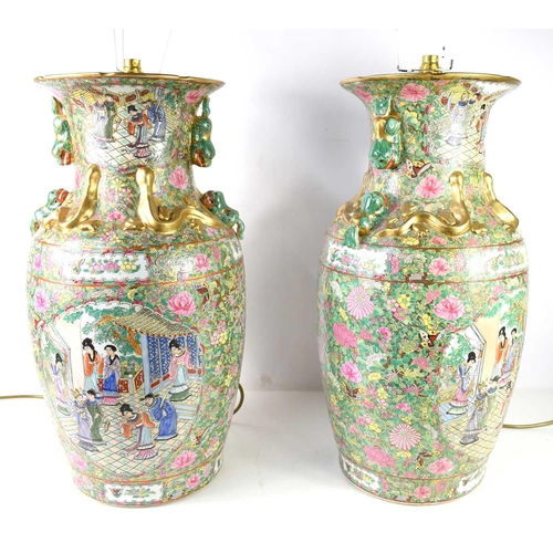 296 - A pair of 20th century Chinese Famille Rose vasiform lamps, fitted for electric, with red pleated sh... 