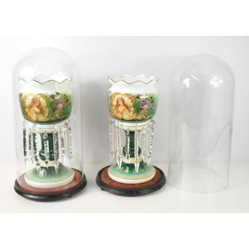 297 - A pair of Victorian glass lustres, within two glass domes, one dome a/f, each decorated with ladies ... 