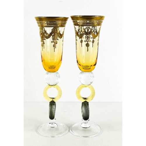 94 - A pair of Bohemian style glass champagne flutes, with amber coloured bowl enhanced with gilded decor... 